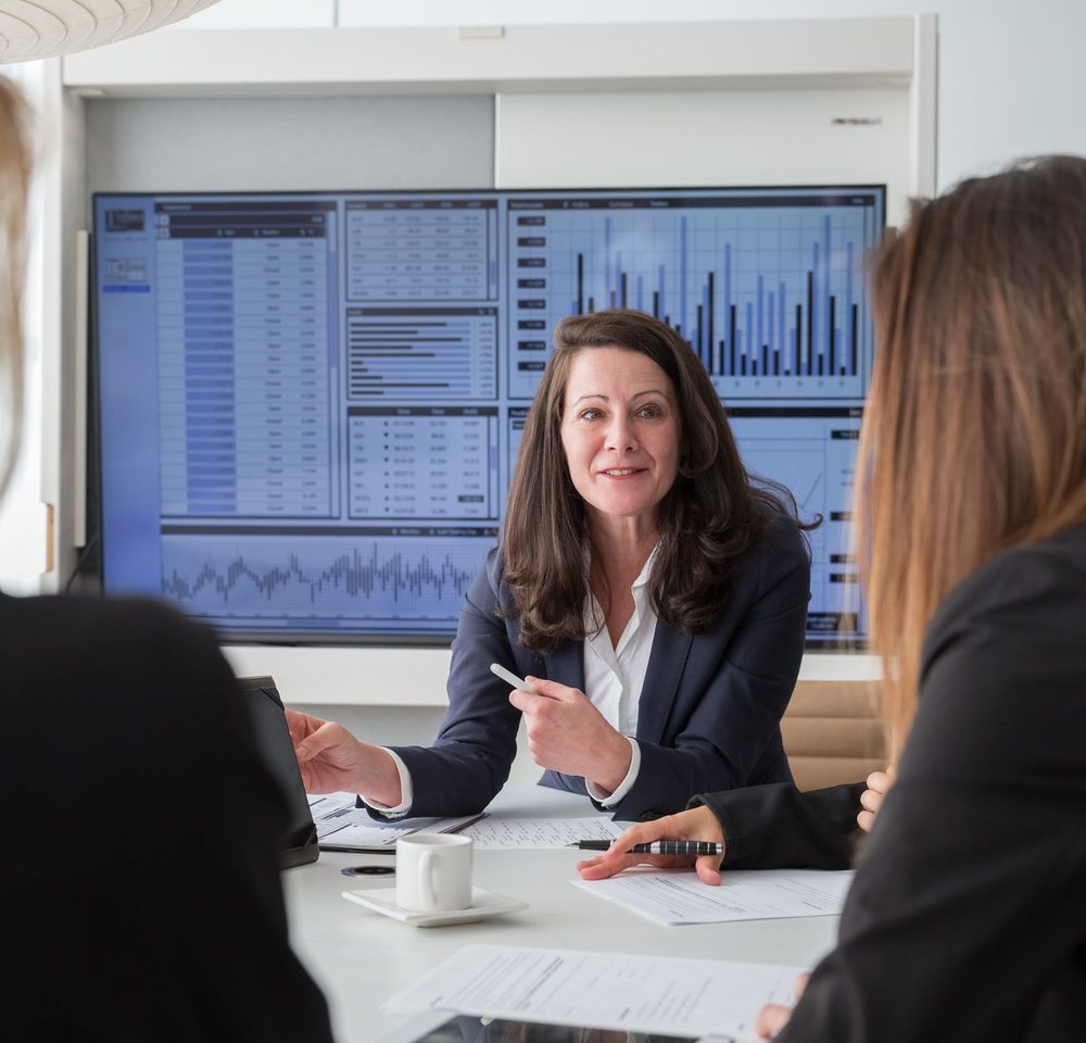 Compliance team reviewing lending dashboards on screen in a board meeting